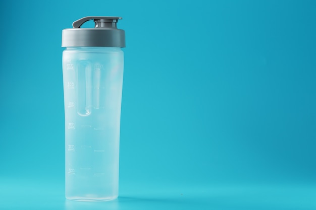 Shaker es un vaso de batido de plástico vacío sobre una superficie azul