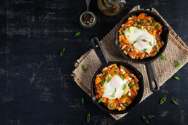 Shakshouka in Bratpfanne Spiegeleier mit Gemüse, Tomaten, Paprika, Kürbis und Zwiebel Draufsicht