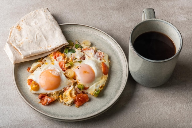 Shakshuka casero, huevos fritos, puerro, pimiento y tomates en un plato gris. cocina mediterranea