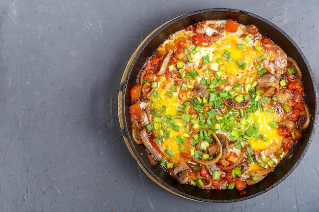 Shakshuka com ervas em uma frigideira em um fundo cinzacopiar foto horizontal do espaço