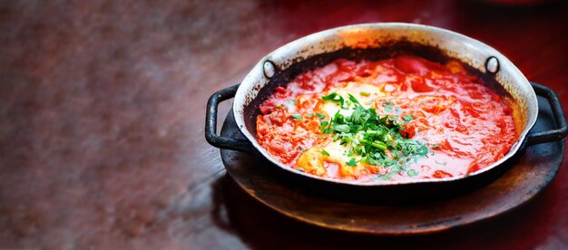 Shakshuka Comida tradicional judaica e receita de cozinha do Oriente Médio Ovos fritos tomates pimentão e salsa em uma panela Feche o foco seletivo Efeito tonificado