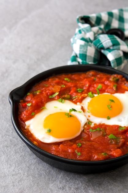 Shakshuka in der Eisenpfanne auf grauem Tisch. Typisches Essen in Israel.