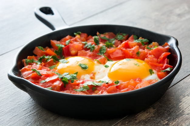 Shakshuka na frigideira de ferro na mesa de madeira Comida típica em Israel.