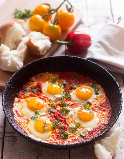 Shakshuka con pan en una mesa de madera. Plato tradicional de Oriente Medio. Hecho en casa. Enfoque selectivo.