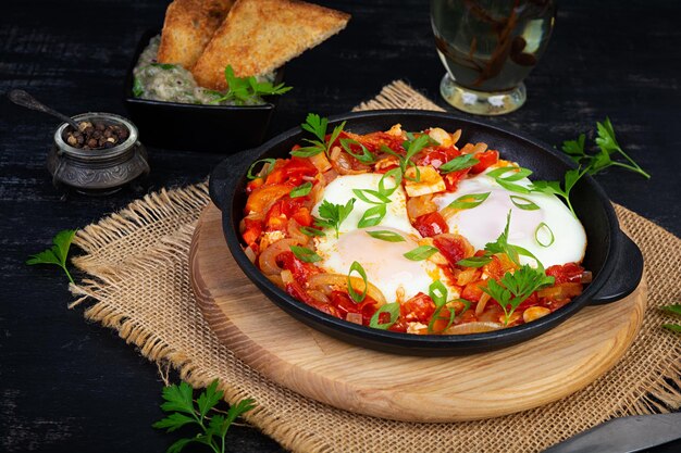 Foto shakshuka con pan a la parrilla huevos fritos con tomate pimienta ajo y hierbas