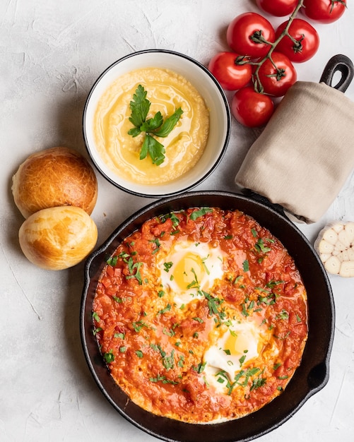 Shakshuka con pimiento, tomates, hummus y panecillos. Vista superior, lugar para texto.