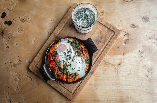 Shakshuka en una sartén y un vaso de ayran comida sana y sabrosa