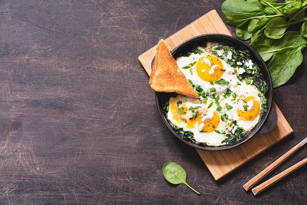 Shakshuka verde en una sartén de hierro fundido huevos fritos con espinacas y tostadas fritas desayuno saludable