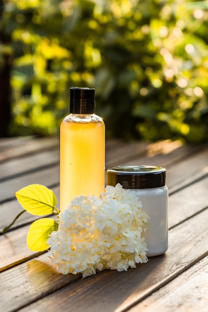 Shampoo e condicionador de cabelo ficam em uma mesa de madeira perto da flor de hortênsia.