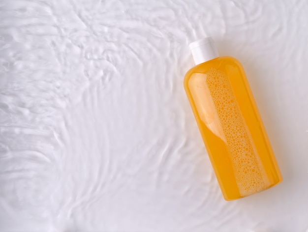 Shampoo, gel de banho, sabonete líquido laranja com ingredientes naturais em um frasco transparente sobre um fundo claro na água