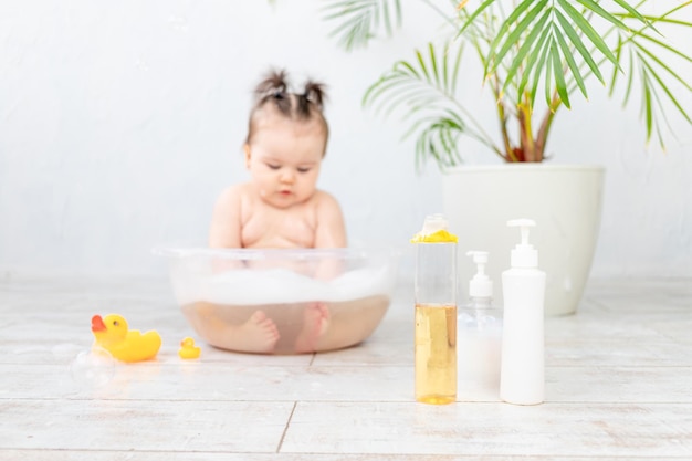 Shampooflaschen im Fokus vor dem Hintergrund eines Babywaschens in einem Becken mit Schaumraum für Text auf Flaschen Babyhygiene