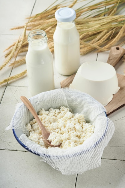 Shavuot jüdische Feiertagsfeier Milch und Käse reifer Weizen und Obstcreme alter rissiger Fliesenwandhintergrund Milchprodukte auf weißem Holzhintergrund Shavuot-Konzept Ansicht von oben Mock-up