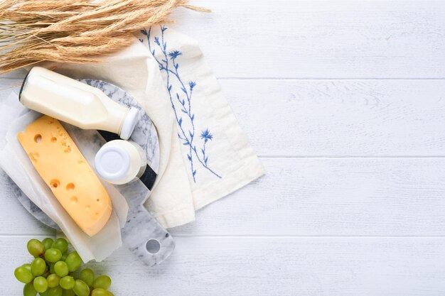 Shavuot jüdische Feiertagsfeier Milch und Käse reifer Weizen und Obstcreme Milchprodukte auf weißem Holzhintergrund Shavuot-Konzept Ansicht von oben Mock-up