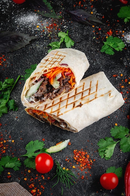 Shawarma burrito cortado com legumes e ervas em uma mesa de pedra escura o conceito de restaurantes de fast food