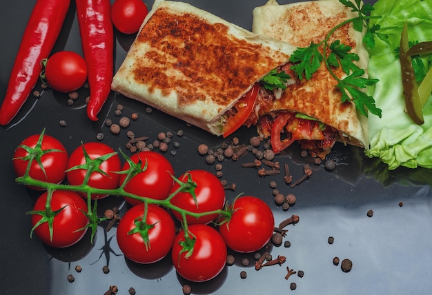 Shawarma cortado ao meio com carne de frango em um fundo preto Vista de cima Queijo pimenta vermelha Salsa Comida de rua Fast Food Comida oriental