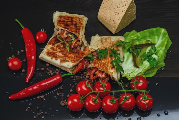 Shawarma cortado por la mitad con carne de pollo sobre un fondo negro Vista desde arriba Queso pimiento rojo