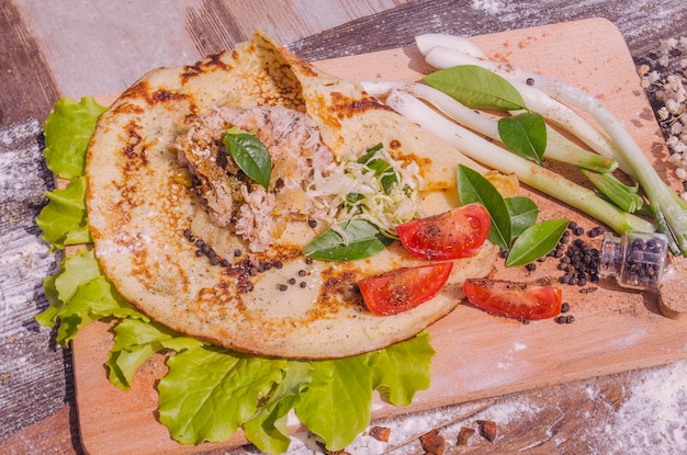 Shawarma em pão pita fino com frango e legumes em uma mesa de madeira