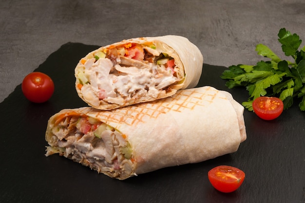 Shawarma grande sabroso con verduras y pollo sobre un fondo oscuro