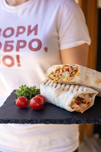 Shawarma mit Fleisch und Gemüse auf einem schwarzen Brett