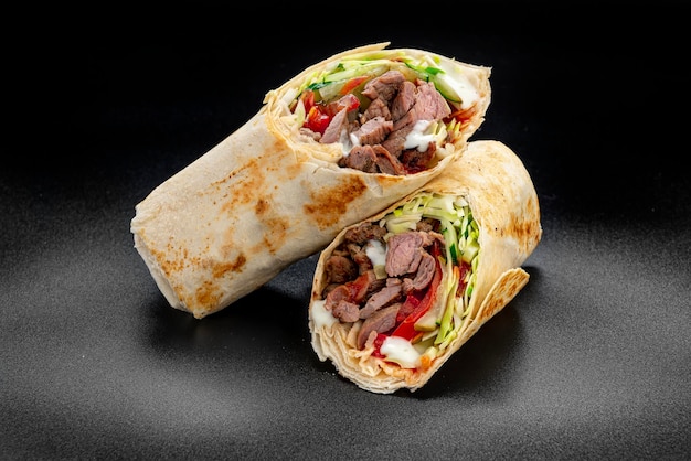 Shawarma de ternera sobre un fondo oscuro Shawarma con ternera en pan de pita