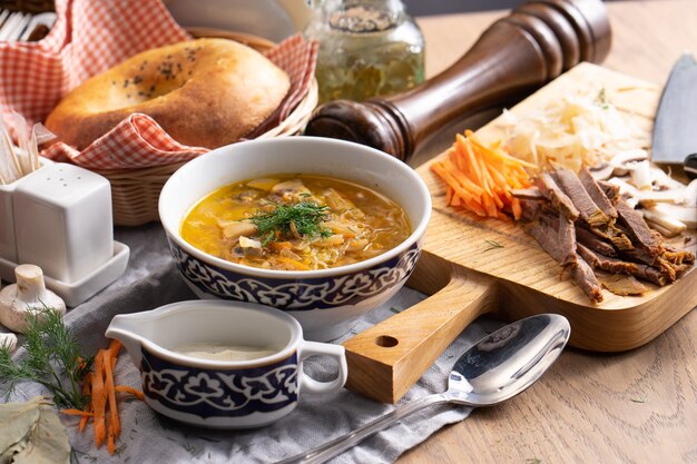 Shchi com creme de leite - uma sopa de vegetais tradicional russa feita de repolho, batata, cenoura e cogumelos em um prato com um uzbeque tradicional