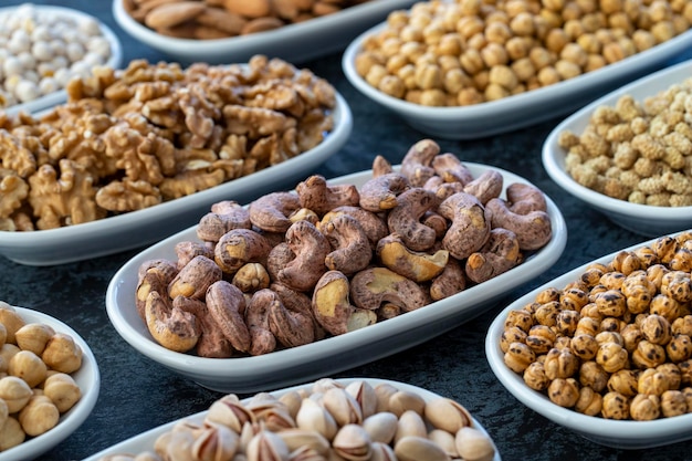 Shell-Cashew in selektiven Fokus Nüsse auf dem Teller auf dunklem Hintergrund Walnuss-Kichererbsen Weiße Kichererbsen Trockene Maulbeer-Mandel-Cashew-Pistazien Arten von Nüssen auf dem Teller