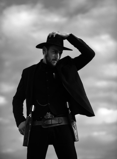 Foto sheriff en traje negro y sombrero de vaquero hombre del oeste salvaje del oeste con revólver de pistola vintage y mariscal