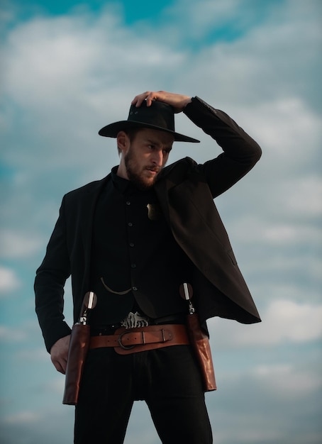 Sheriff en traje negro y sombrero de vaquero Hombre del oeste salvaje con revólver de pistola vintage y municiones de mariscal