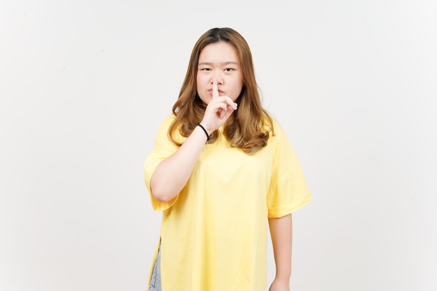 Shh Be Quiet de uma linda mulher asiática vestindo camiseta amarela isolada em fundo branco