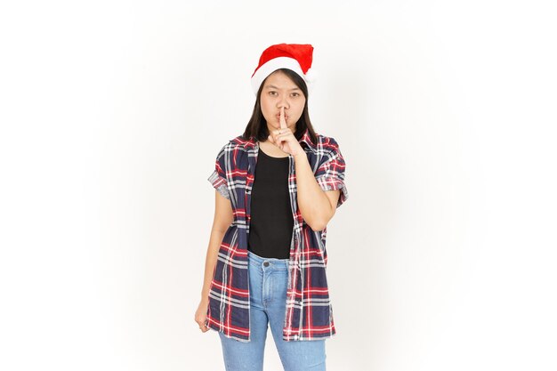 Shh, cállate de la hermosa mujer asiática con camisa a cuadros roja y gorro de Papá Noel aislado en blanco