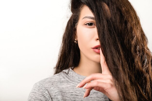 Shh fique quieto gesto de silêncio mistério secreto. Jovem mulher mostrando sinal de silêncio, silenciando o dedo no cabelo dos lábios, cobrindo os olhos.