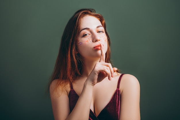 Shh. Silencio. Mujer joven pelirroja con el dedo en los labios.