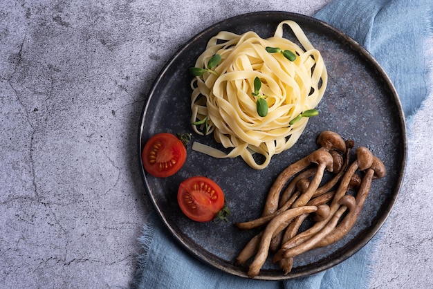 Shimeji frito servido com macarrão em cogumelos de prato e macarrão em fundo cinza