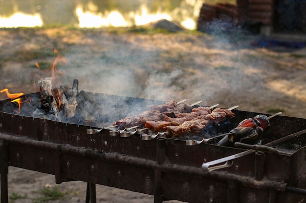 Shish kebab apetitoso asado con humo en brochetas en la parrilla de carbón al aire libre