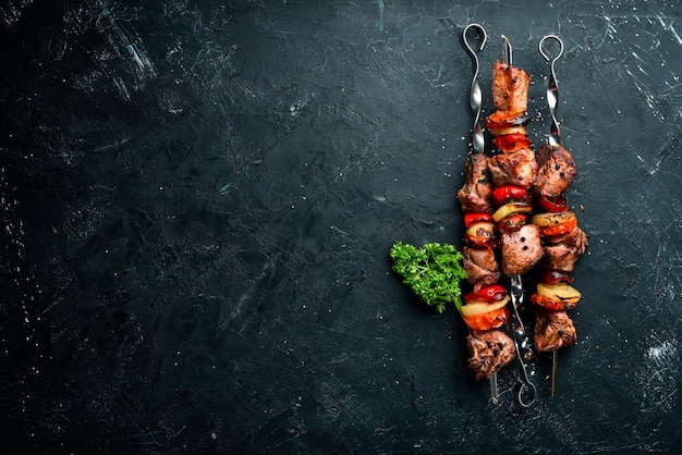 Shish kebab Carne a la barbacoa con cebollas y tomates Sobre un fondo negro Vista superior Espacio libre para su texto Estilo rústico