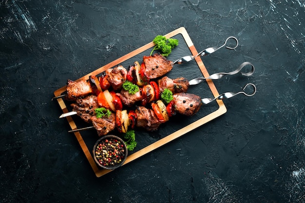 Shish kebab Carne a la barbacoa con cebollas y tomates Sobre un fondo negro Vista superior Espacio libre para su texto Estilo rústico