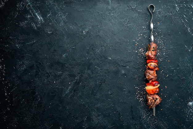 Shish kebab Carne de churrasco com cebola e tomate Em um fundo preto Vista superior Espaço livre para o seu texto Estilo rústico