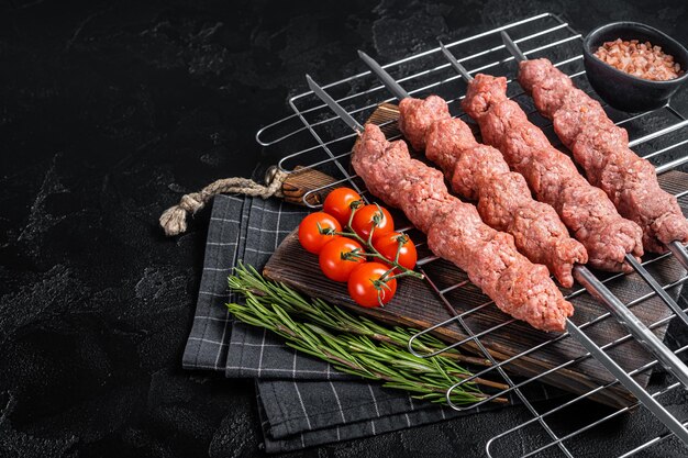 Shish kebab cru de carne moída de cordeiro e carne de bovino kebab turco adana em espetos fundo preto vista superior copiar espaço