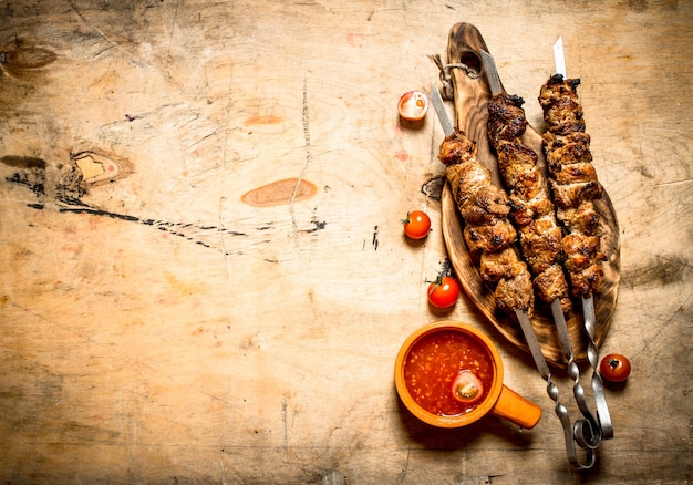 Shish kebab con salsa de tomate. Sobre una mesa de madera.