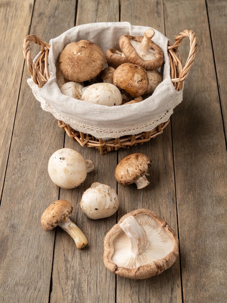 Shitake portobello y champiñones parís en una cesta sobre una mesa de madera