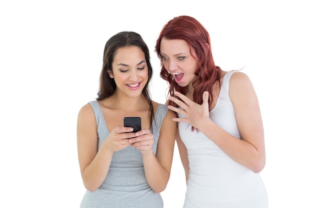 Shocked jovens amigas que olham para celular