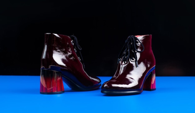 Shopping-Konzept weibliche Leder stilvolle Schuhe Paar modische Lederschuhe High Heel Burgunder Stiefel Stiefeletten auf schwarzem Hintergrund Schuhgeschäft