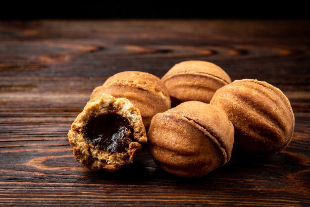 Shortbread en forma de nuez con caramelo en la mesa de madera oscura.