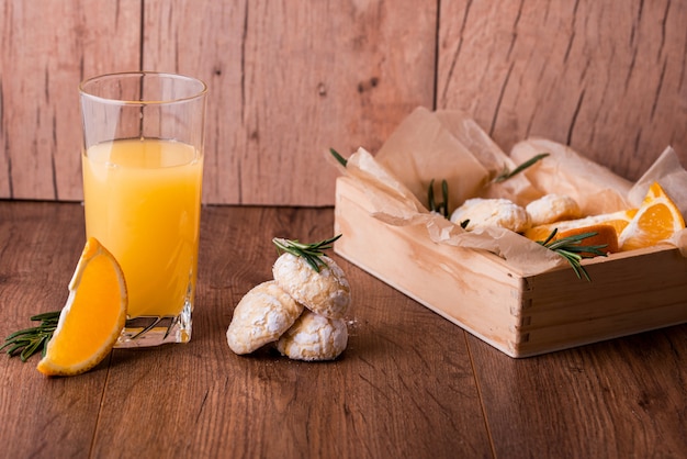 Shortbread-Orangenkekse mit Semarinzweigen, mit frischer Orange und Saft auf dem Tisch.