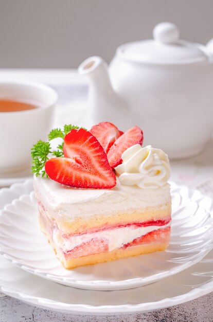 Shortcake de morango caseiro com recheio de molho de morango no prato branco e servir de chá quente. Conceito de tomar o chá da manhã ou da tarde com bolo.