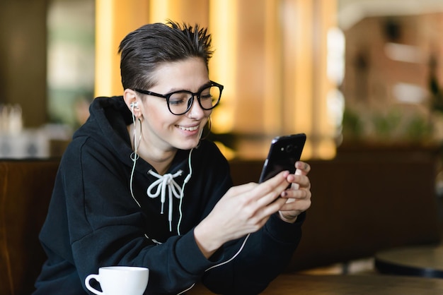 Shortcut-Hipster-Mädchen hört Musik in modernen weißen Kopfhörern, die online mit Freunden kommunizieren