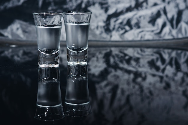 Shots de vodka com gelo na mesa preta, copie o espaço