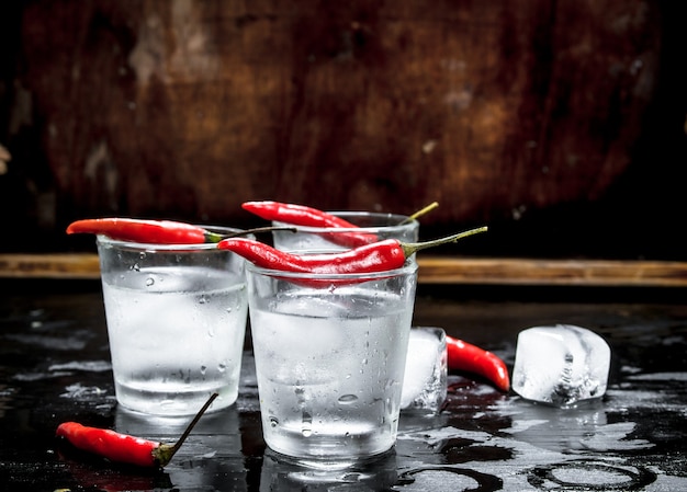 Shots de vodka com pimenta malagueta. Sobre um fundo de madeira.