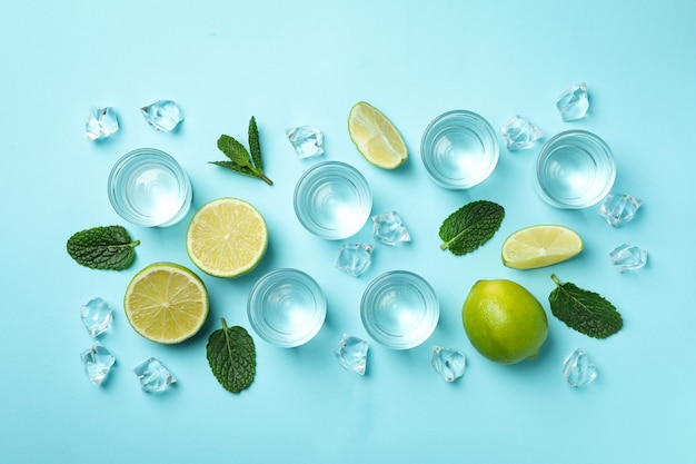 Shots, rodelas de limão, hortelã e cubos de gelo em azul, vista superior