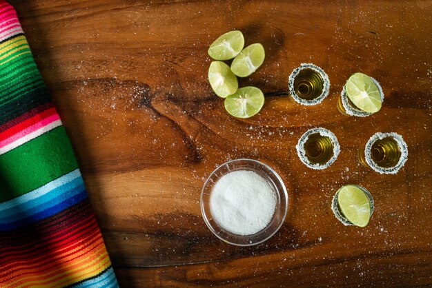 Shots de tequila con sal y limón en una mesa de madera Festivo cinco de mayo de fondo